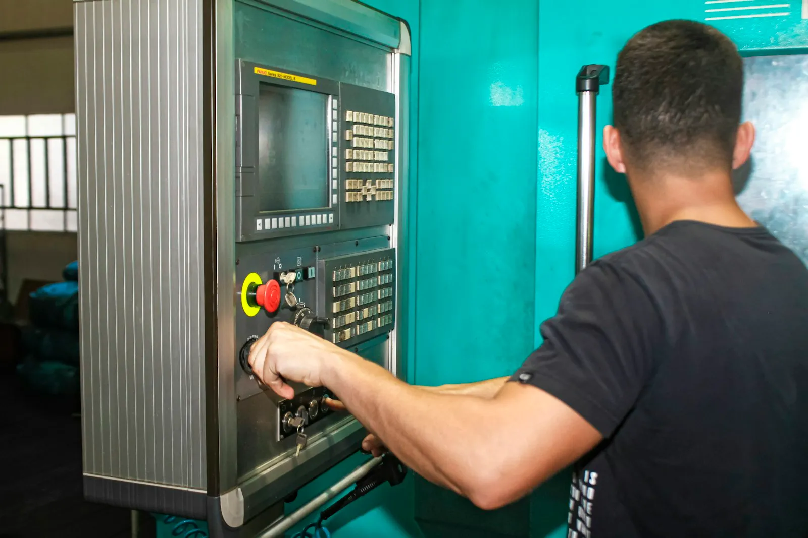 Machinist operating the control panel of a CNC machine