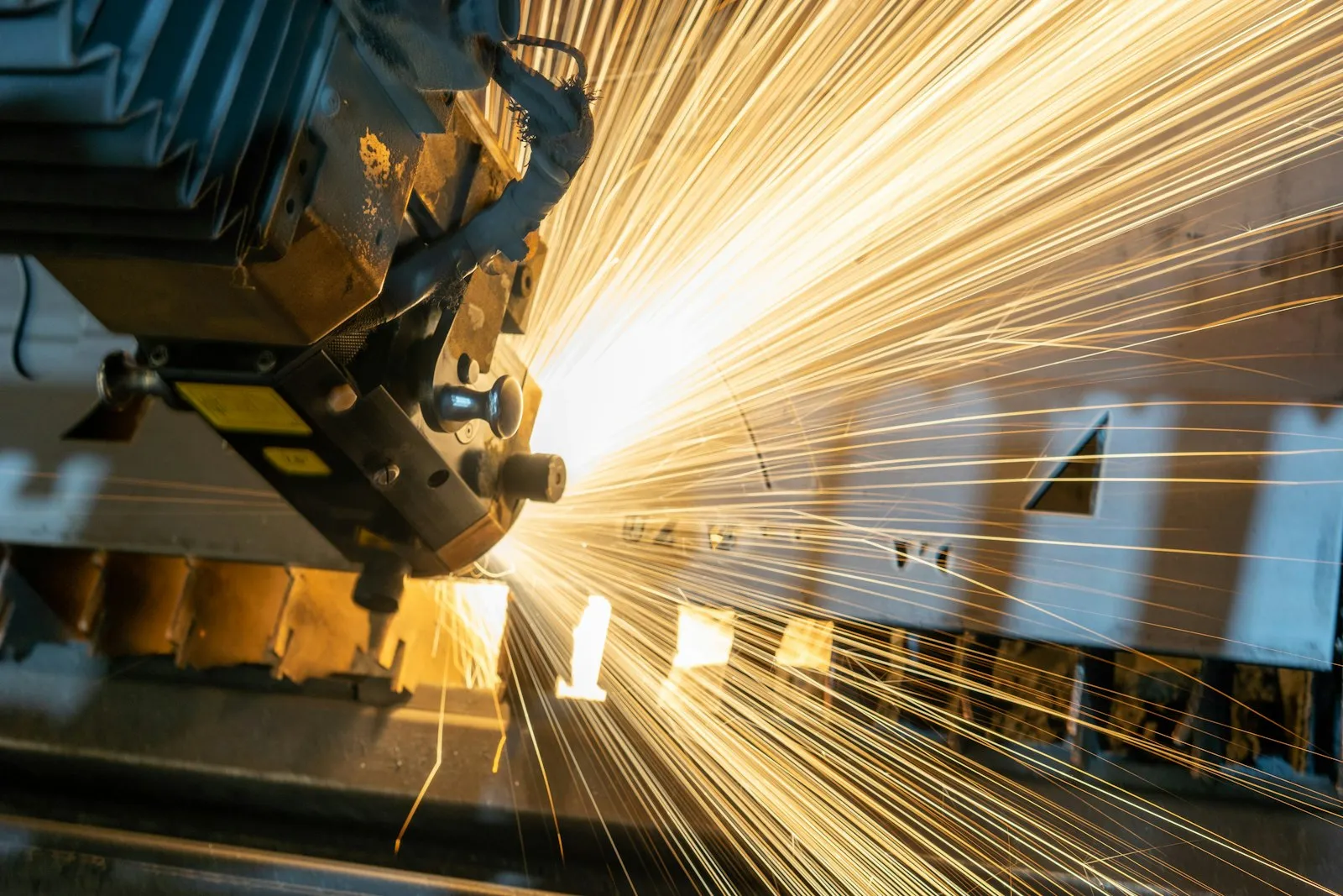 Laser cutting head throwing sparks as it cuts a metal sheet