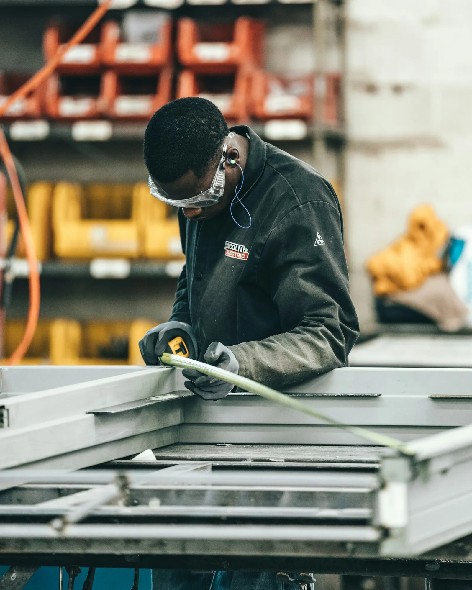 Fabricator measuring a metal frame with a tape measure