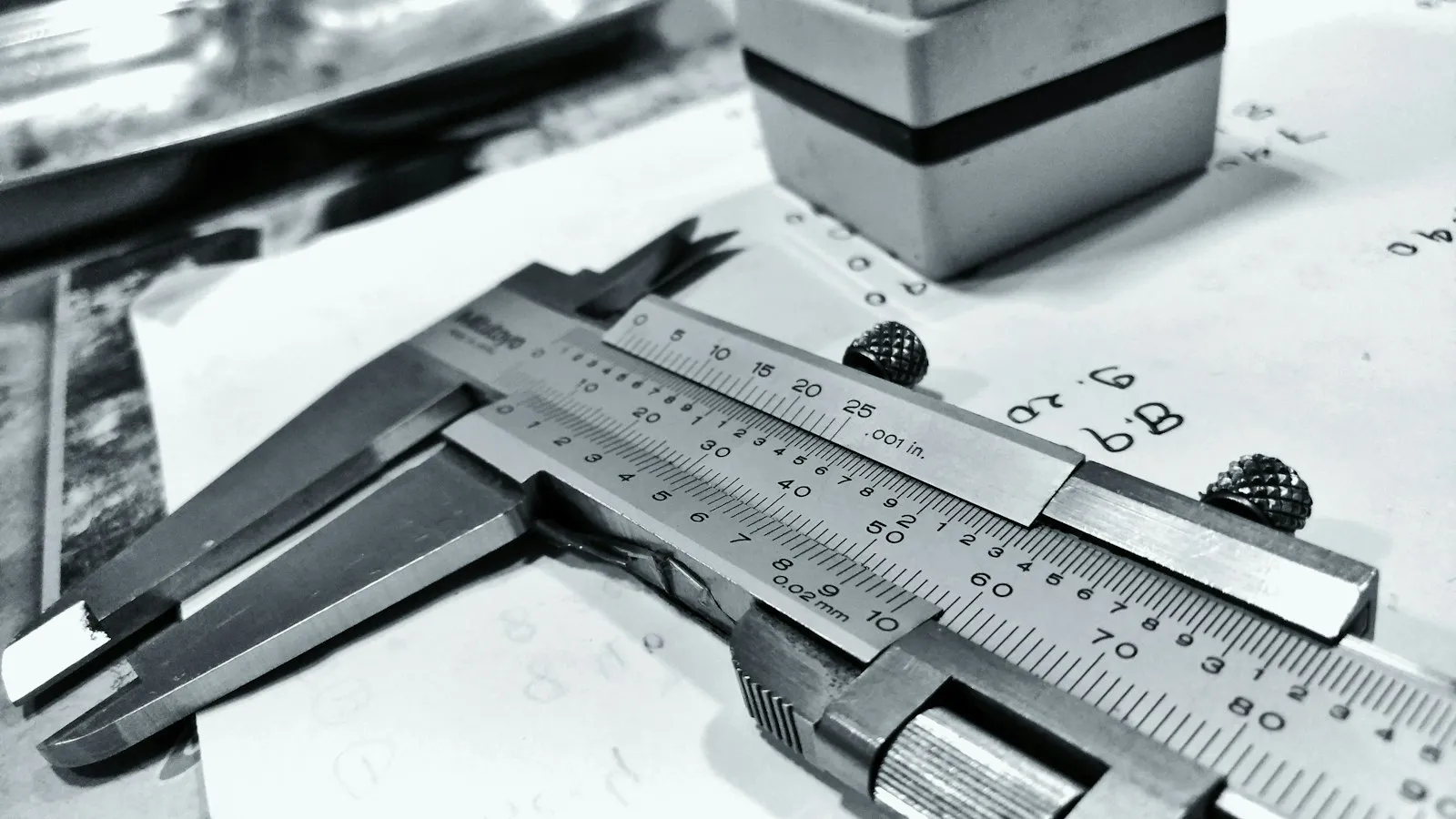 Vernier caliper resting on a drawing with handwritten measurements