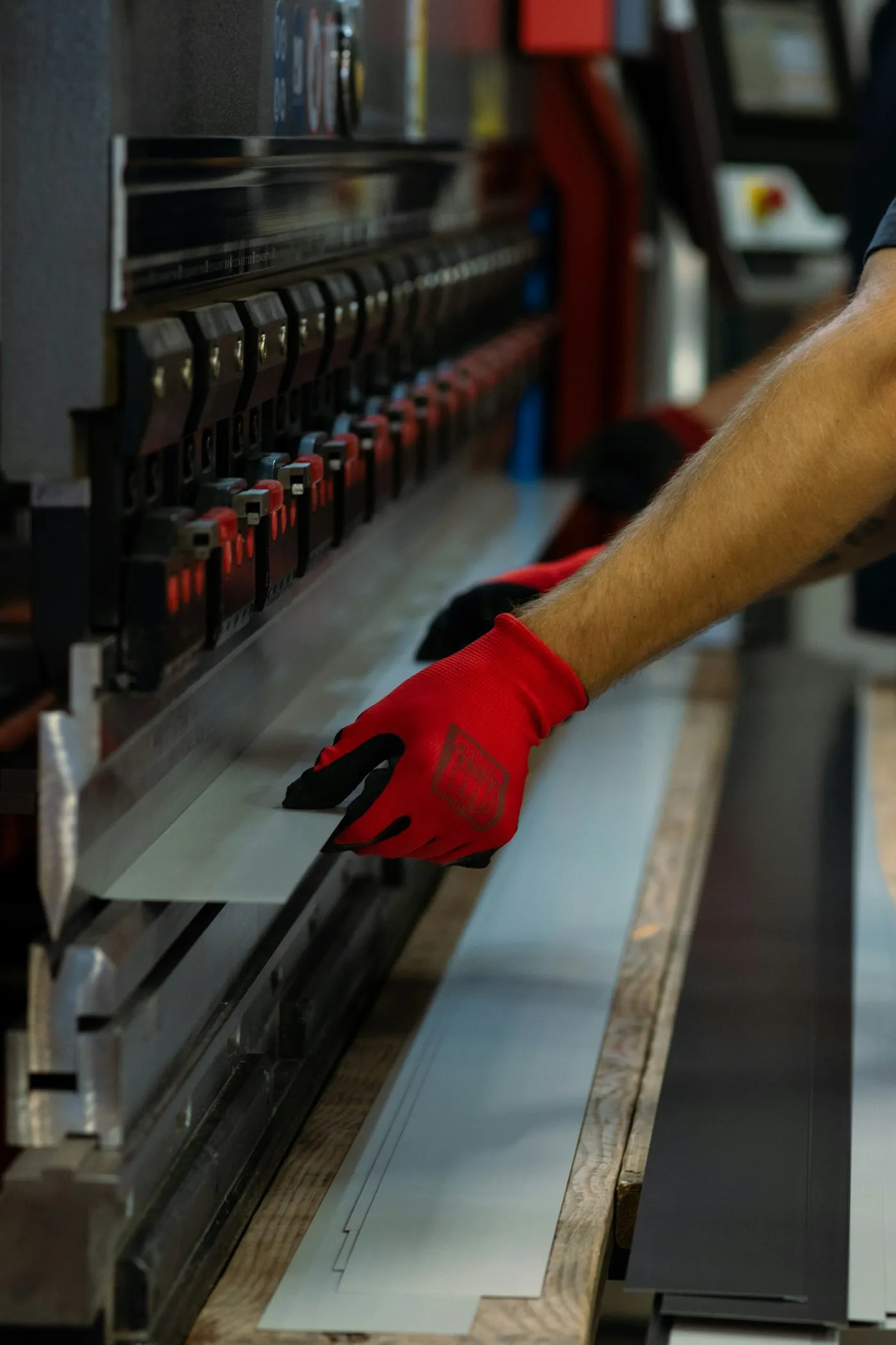 Operator in red gloves feeding sheet into a press brake