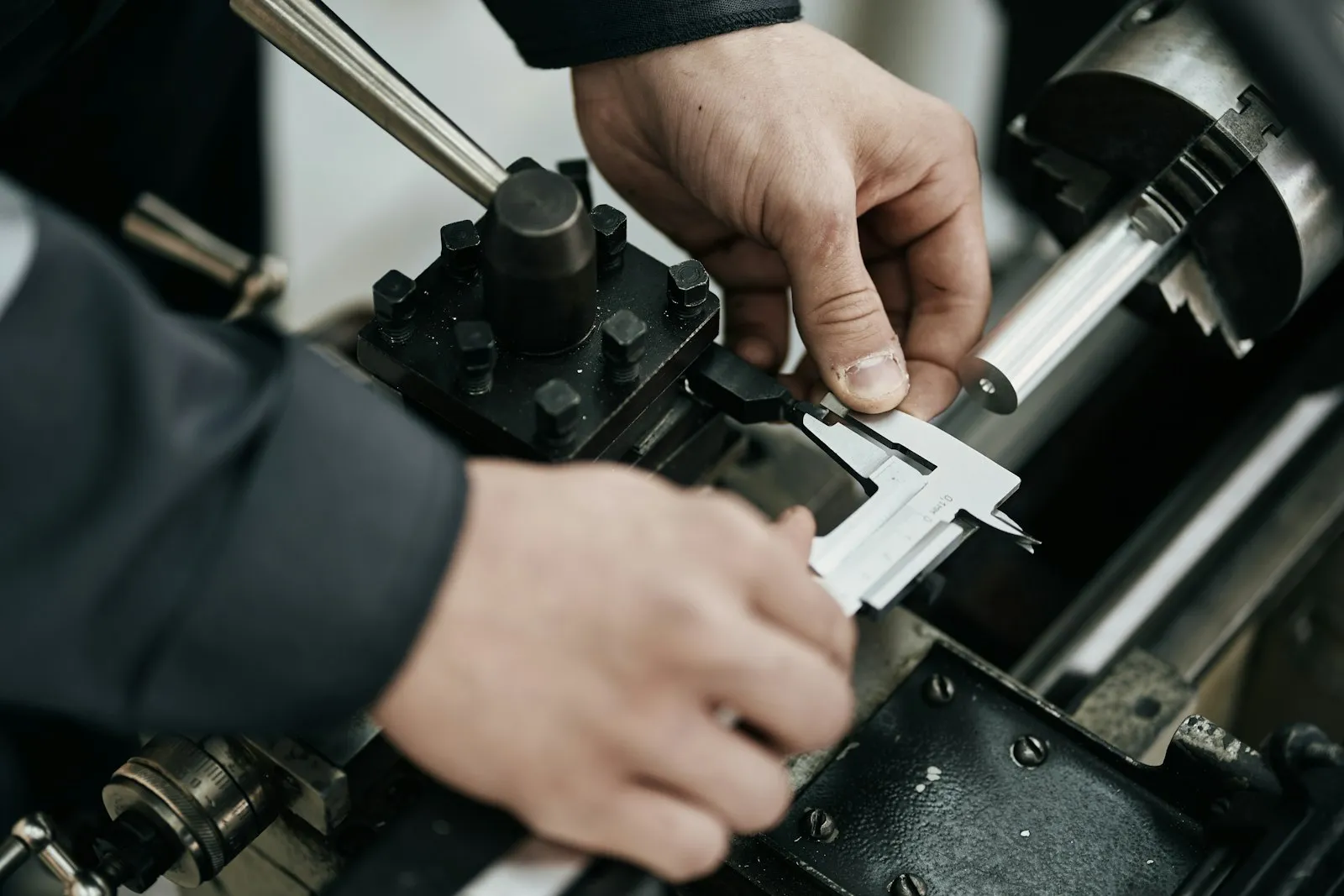 Machinist measuring a turned part with a caliper at the lathe