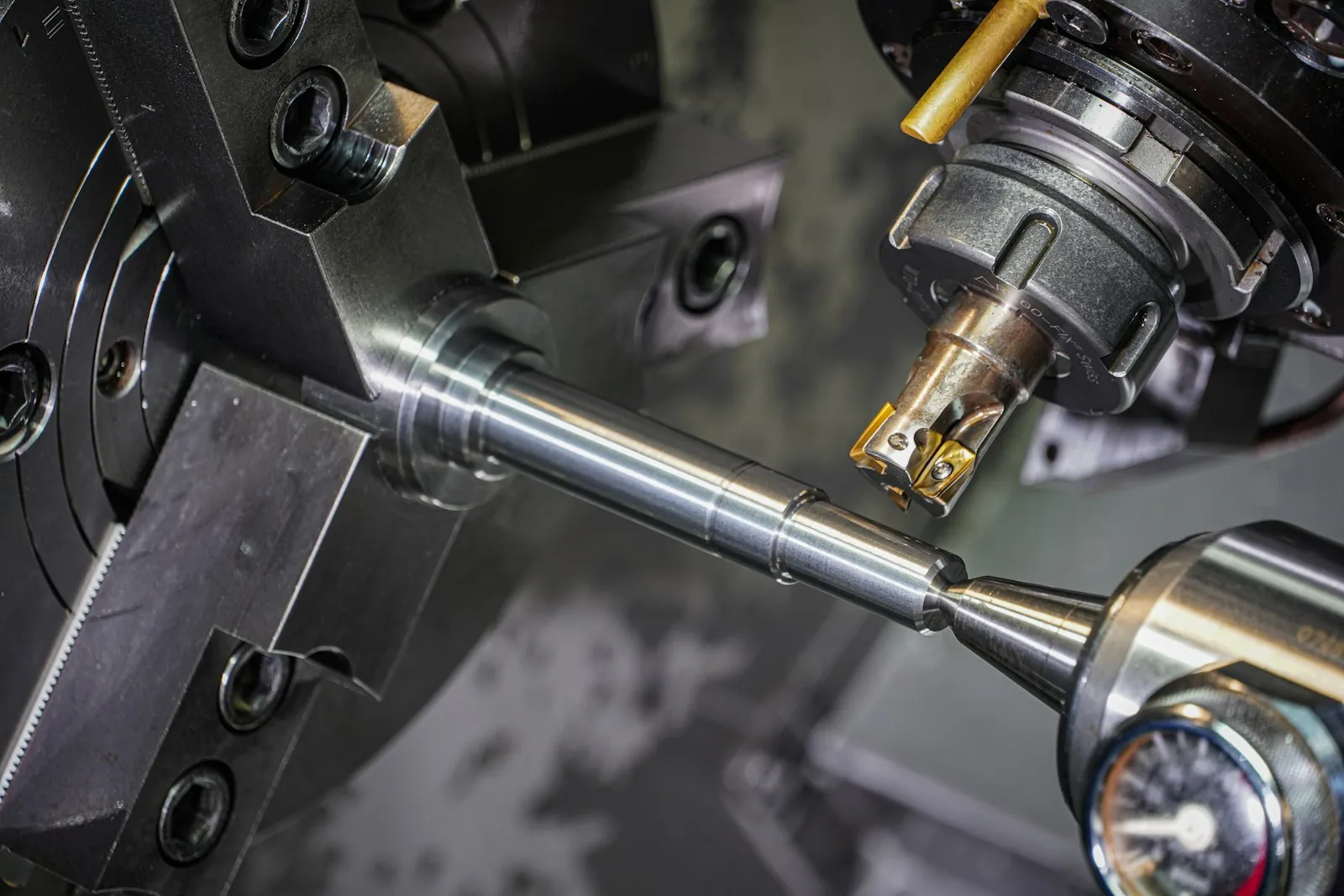 Stepped steel shaft held between a chuck and a tailstock center on a CNC lathe